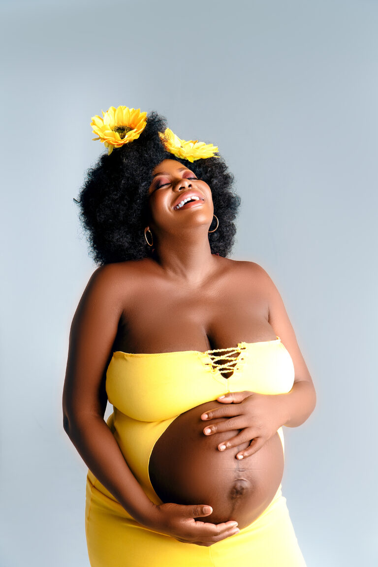 Maternity portrait in a yellow strapless dress with flowers in her hair