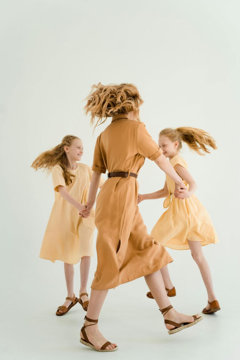 Mother and two daughters dancing in matching neutral outfits