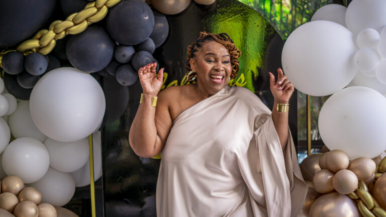 Guest of honour laughing in front of a balloon installation at her milestone birthday
