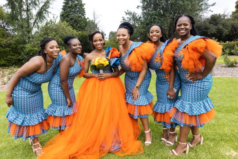 Bride in an orange skirt with her bridesmaids in matching blue and orange dresses