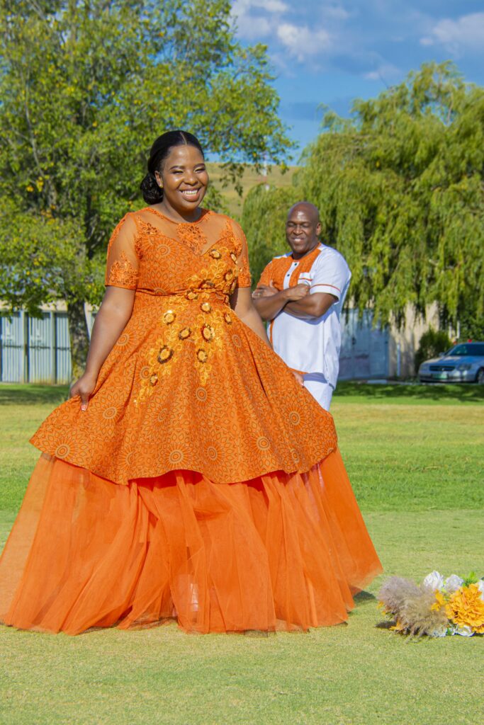 Bride laughing in an orange gown as the groom looks on behind her