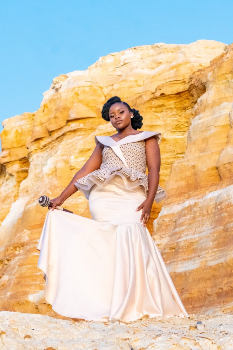 Bride in a cream gown posed against sandstone rocks