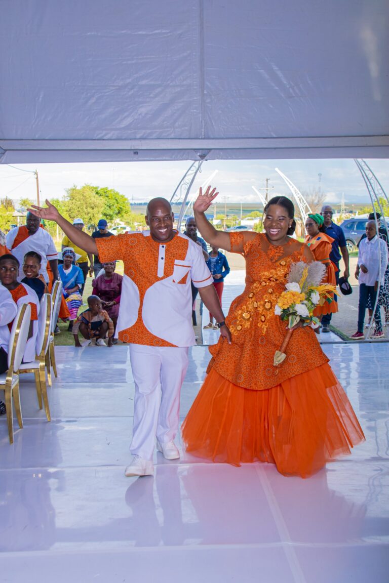 Couple waving to their guests as they walk into the marquee