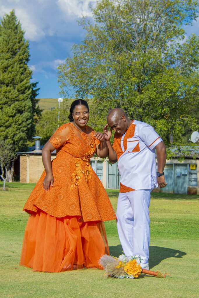 Couple laughing together on the lawn in orange and white attire