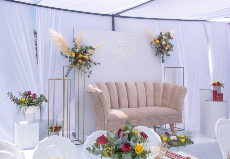 Decorated stage with a blush sofa, gold stands and flowers