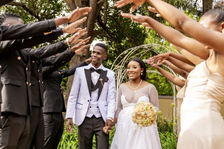 Couple walking under an arch of arms made by the bridal party