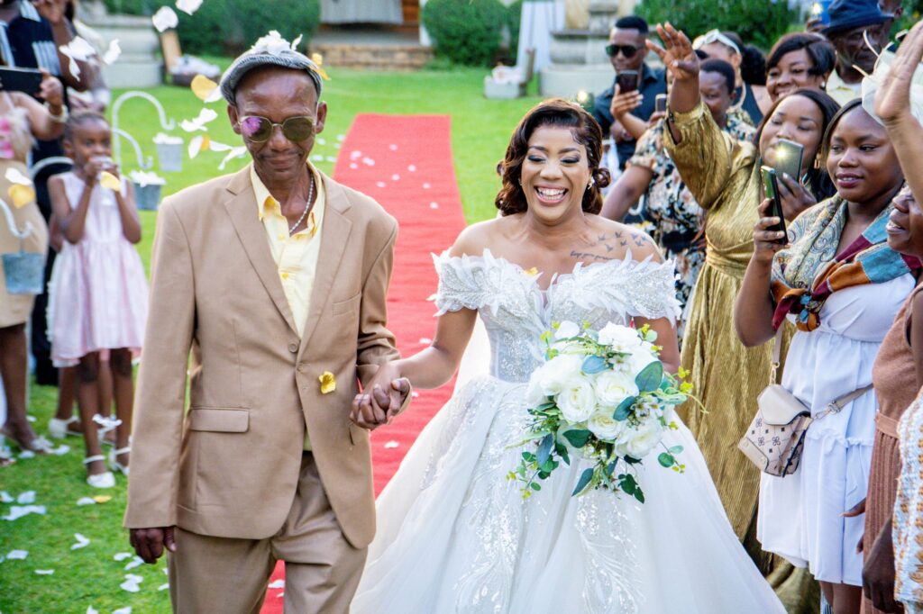 Bride walking down the aisle with her father as guests cheer