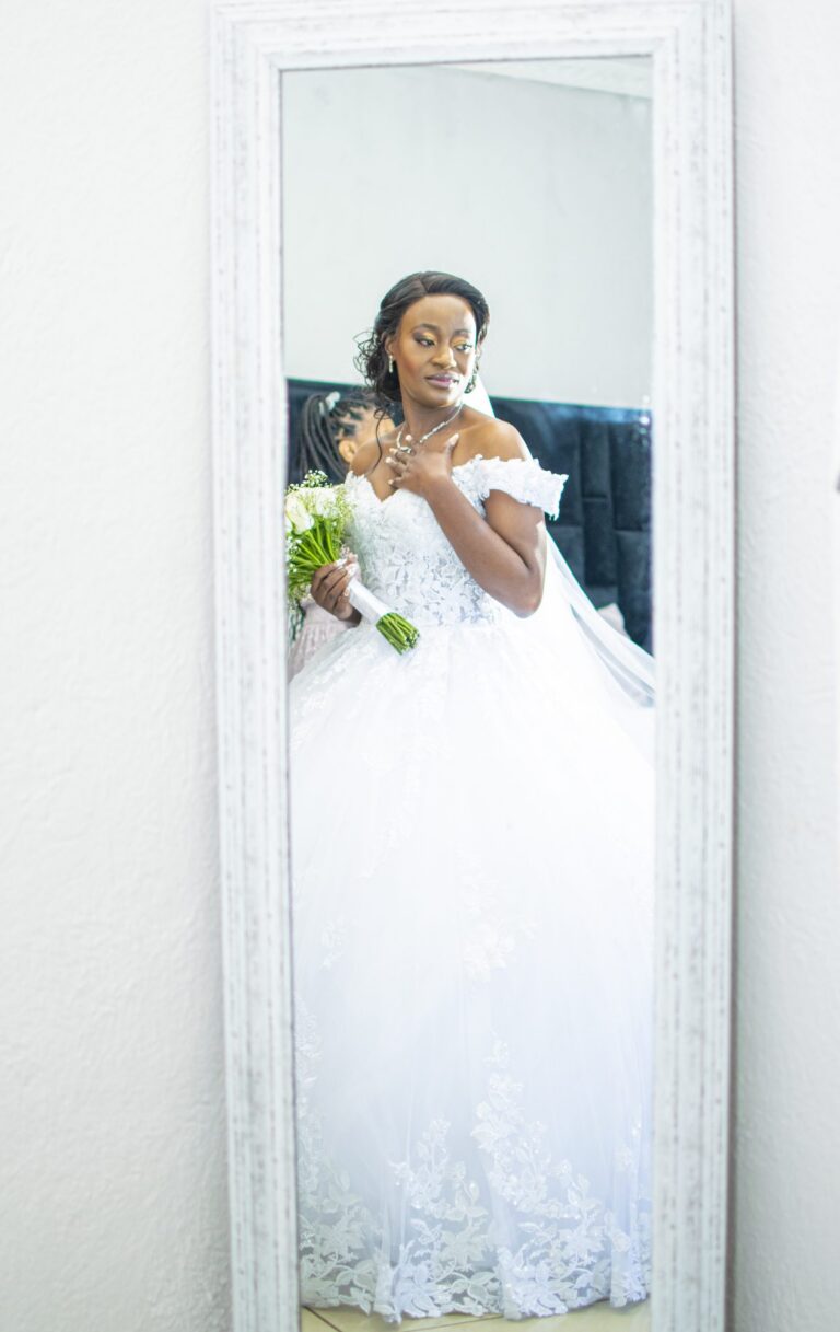 Bride reflected in a tall mirror in her wedding gown