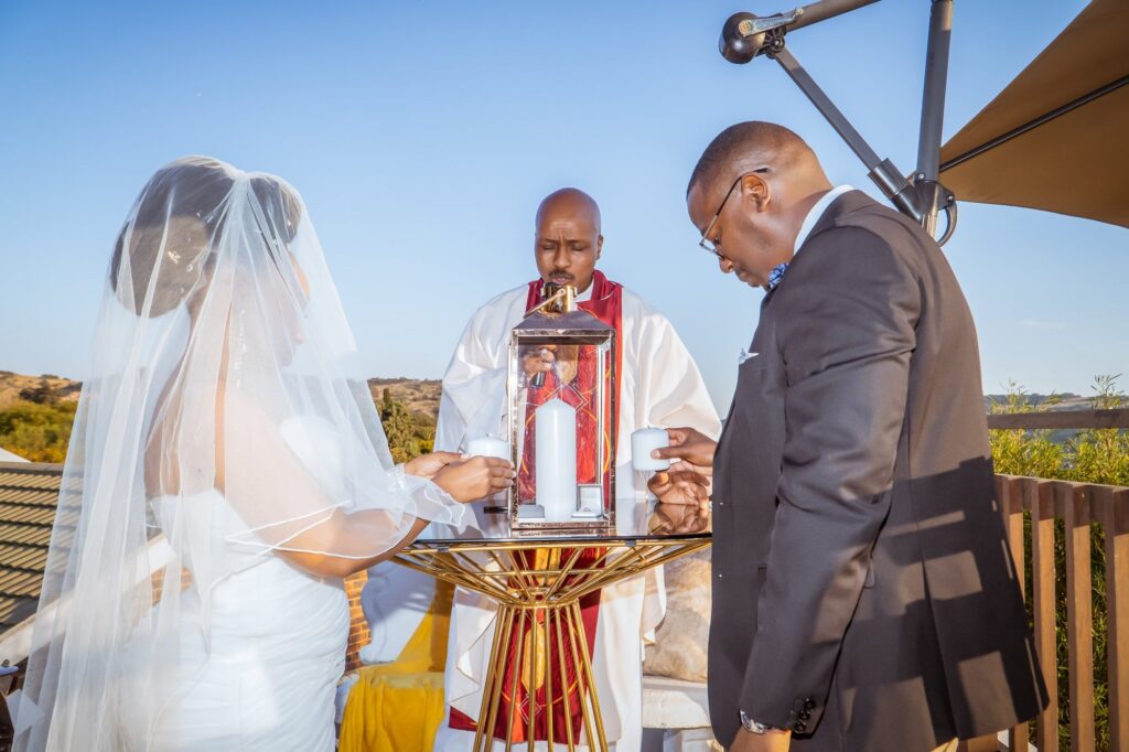 Bride and groom lighting a candle with the minister during the ceremony