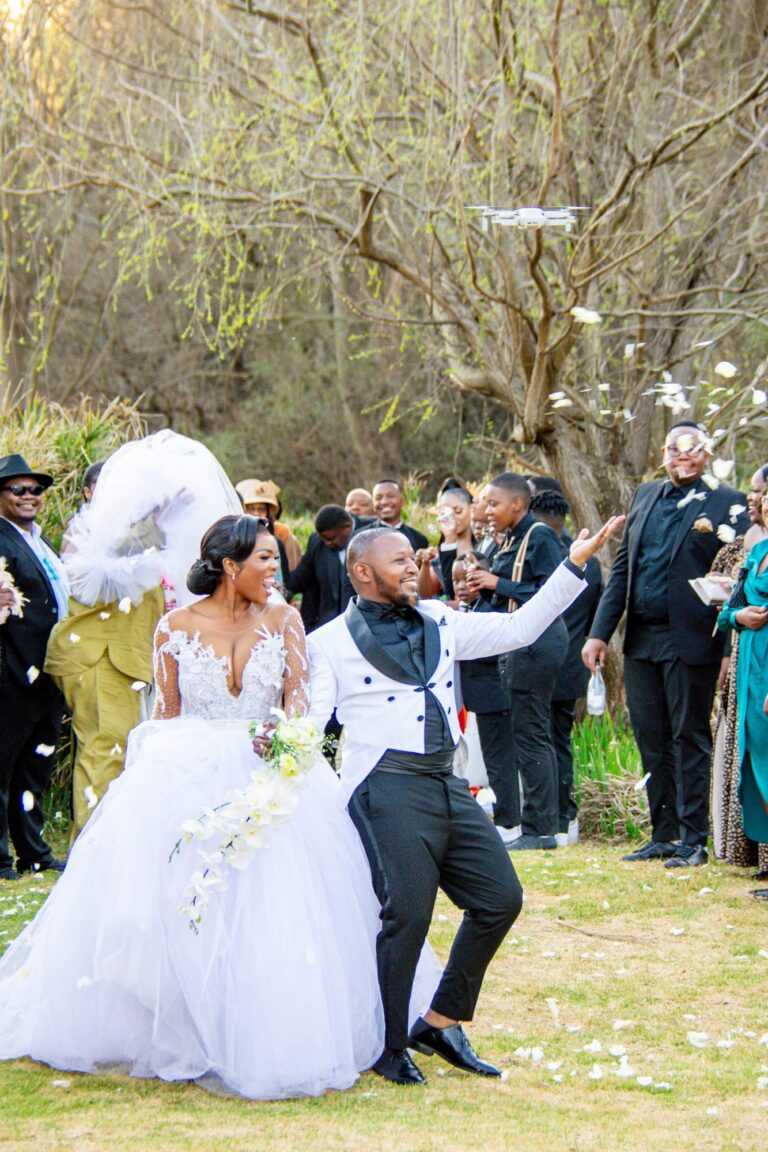 Couple celebrating as guests throw confetti after the ceremony