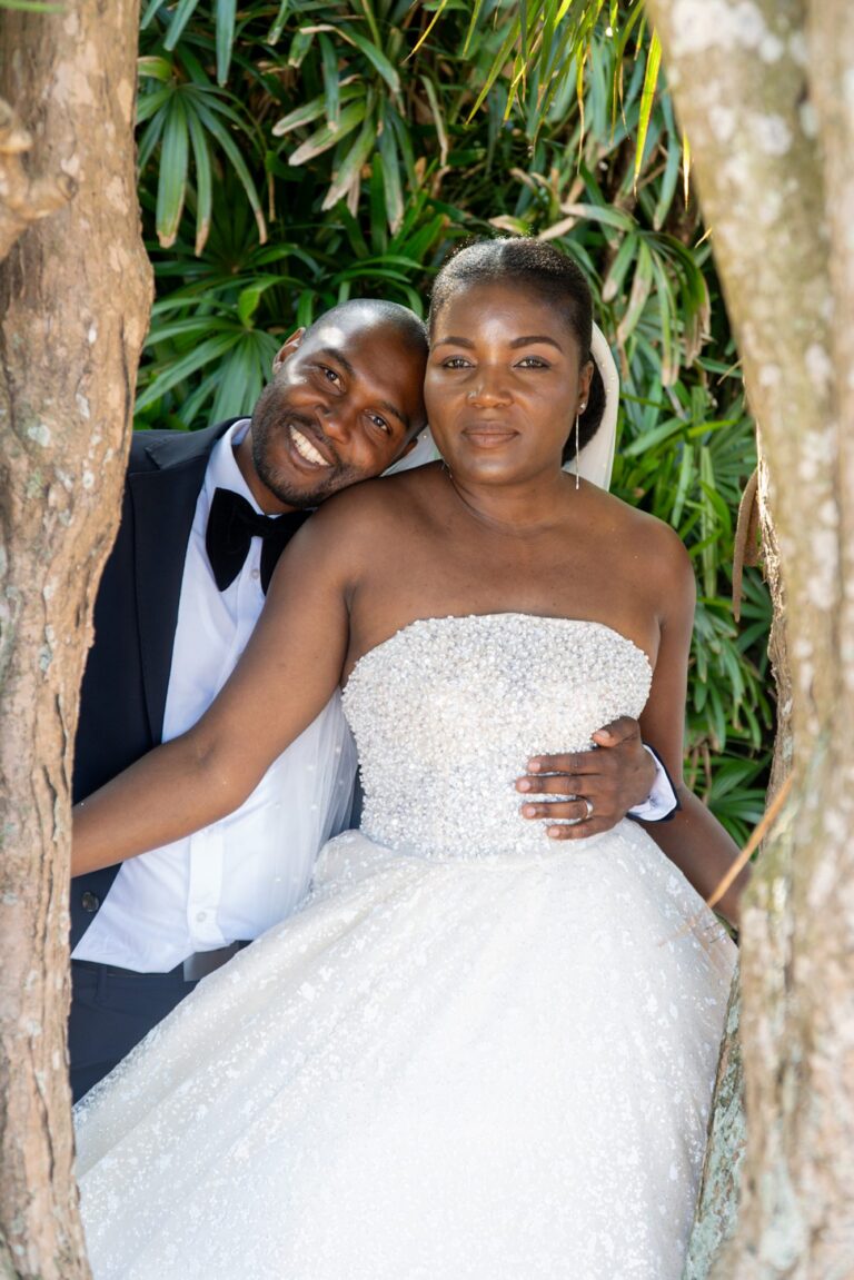 Groom holding his bride between two trees