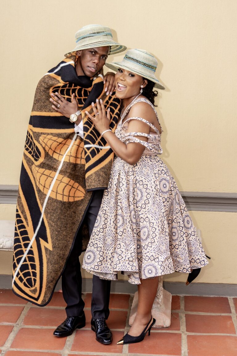 Couple wrapped in a traditional blanket and wearing woven hats