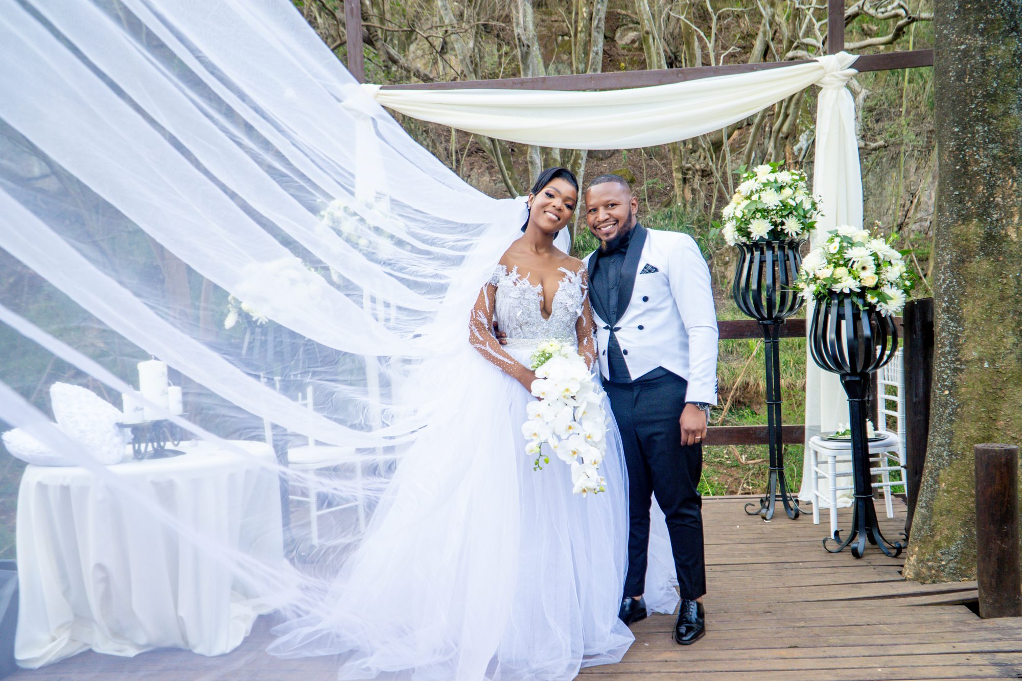 Couple standing under a draped arch as the veil sweeps across the frame
