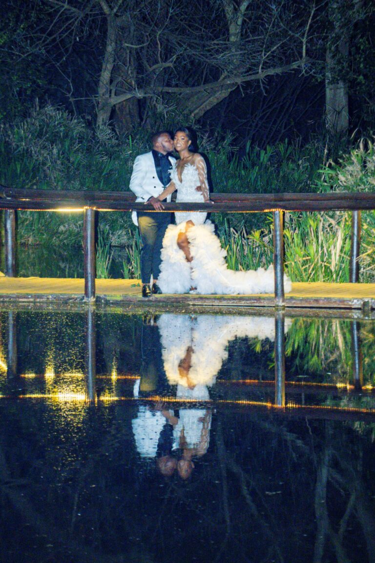 Couple kissing on a deck at night, reflected in the water