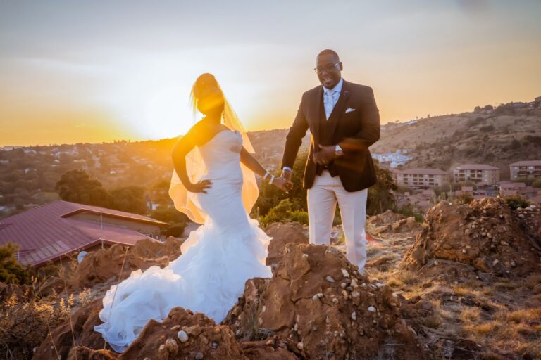 Bride and groom on a hilltop at sunset