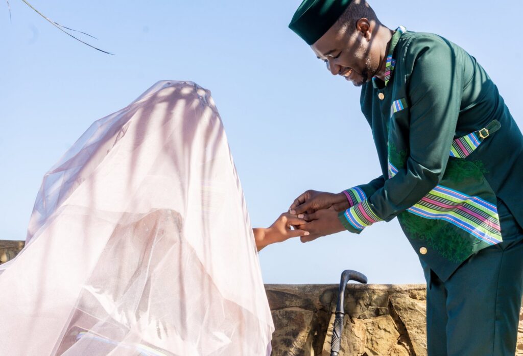 Groom placing a ring on his veiled bride's finger