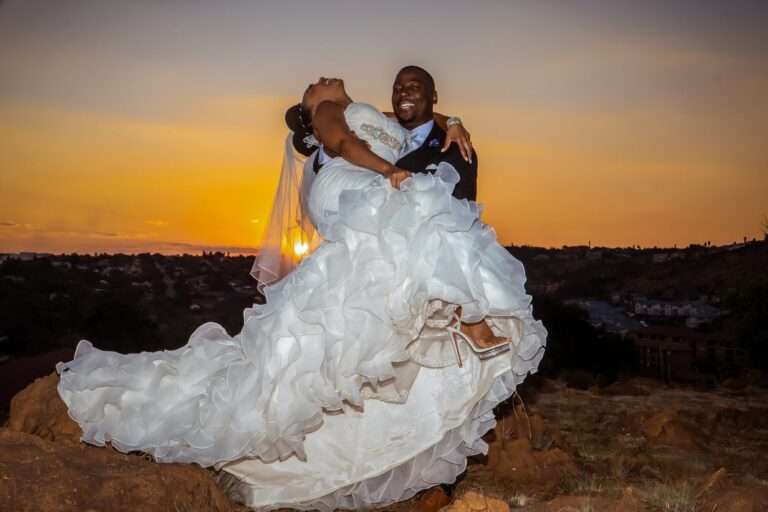 Groom dipping his bride against a sunset sky