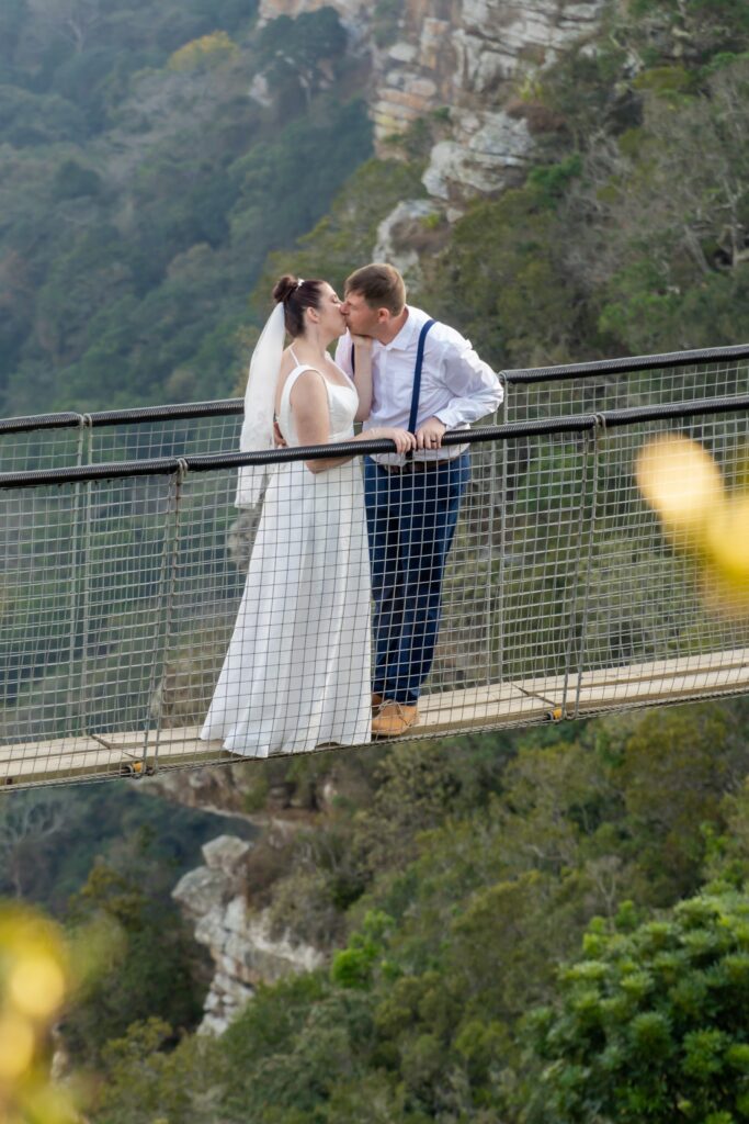 Couple embracing on a suspension bridge above a gorge