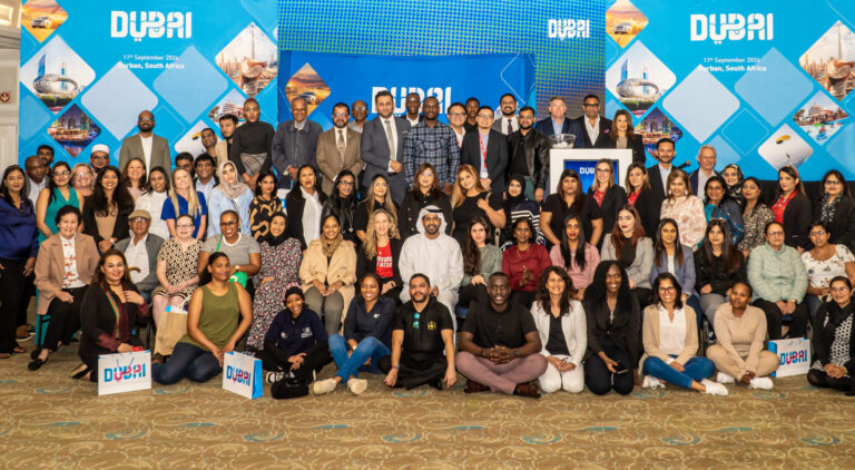 Delegates posing together in front of the Dubai backdrop at the Dubai Tourism roadshow