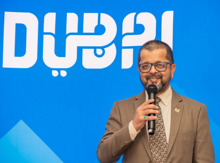Speaker addressing guests in front of the Dubai logo at the Dubai Tourism roadshow