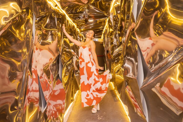 Guest posing in the gold reflective room at the Fossil brand activation