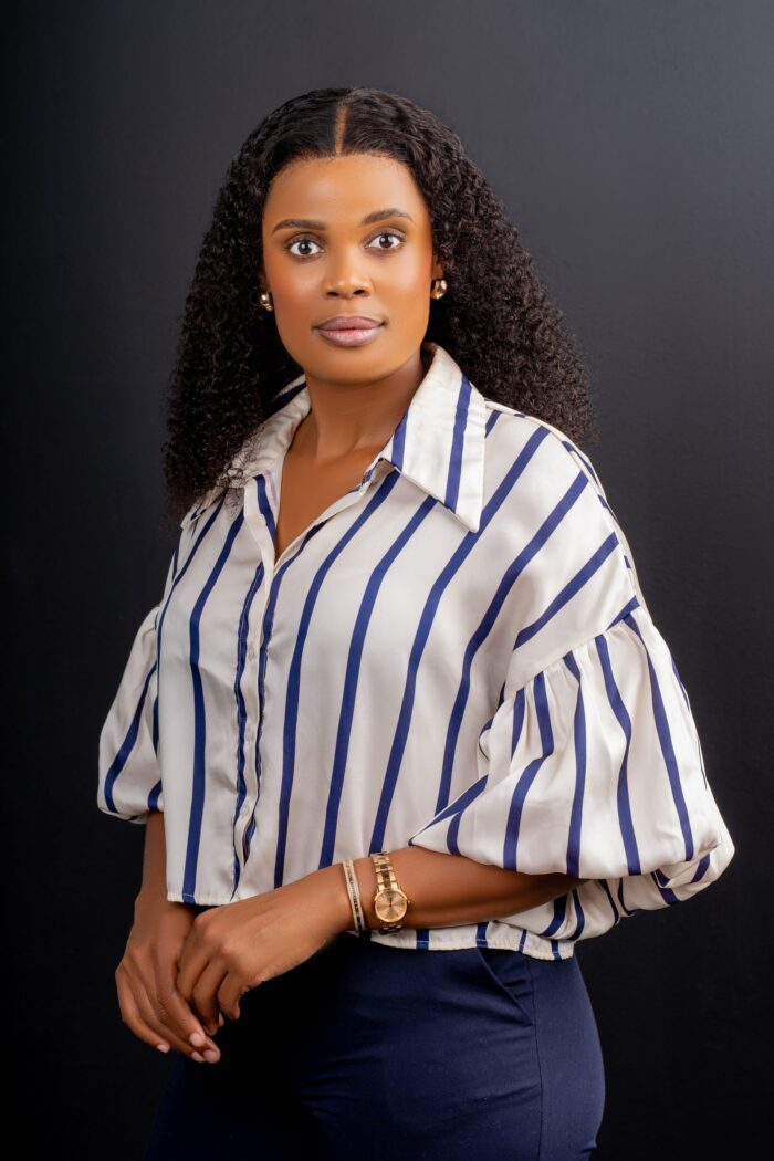 Professional headshot, striped blouse on a dark backdrop, by Studio24.7