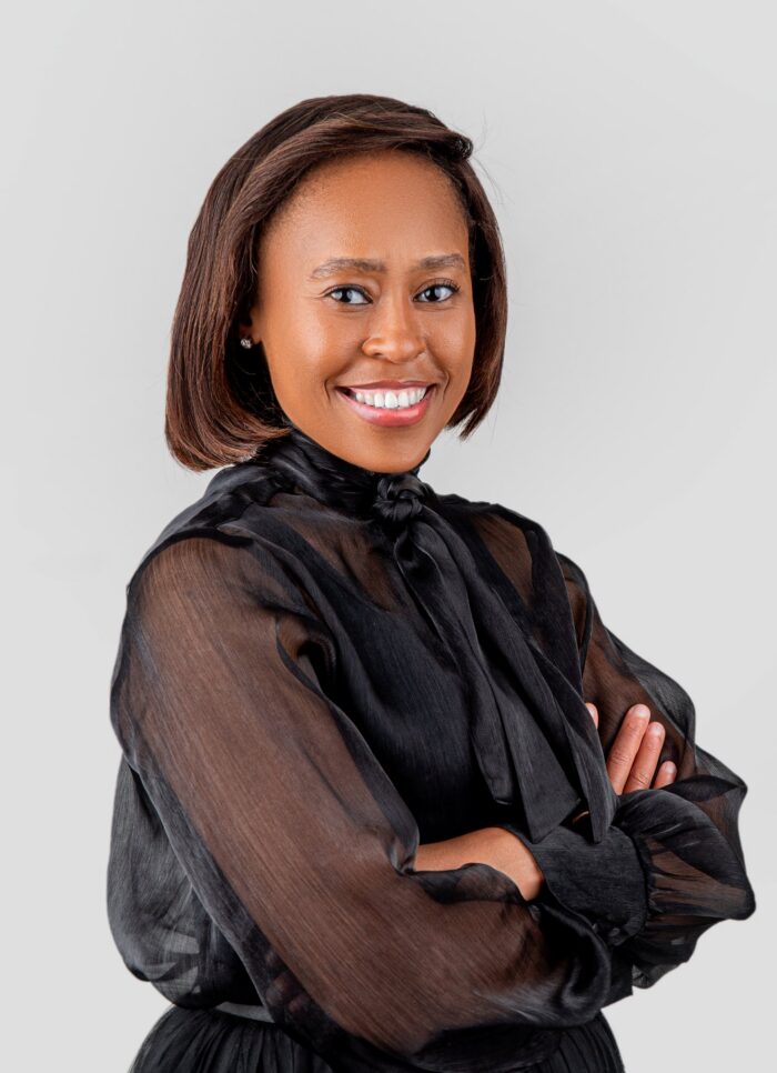 Professional headshot, sheer black blouse, arms crossed, warm smile, by Studio24.7