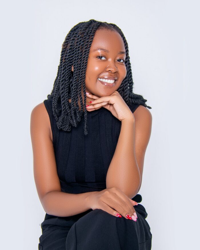 Professional headshot, black sleeveless top, seated pose, hand under chin, by Studio24.7