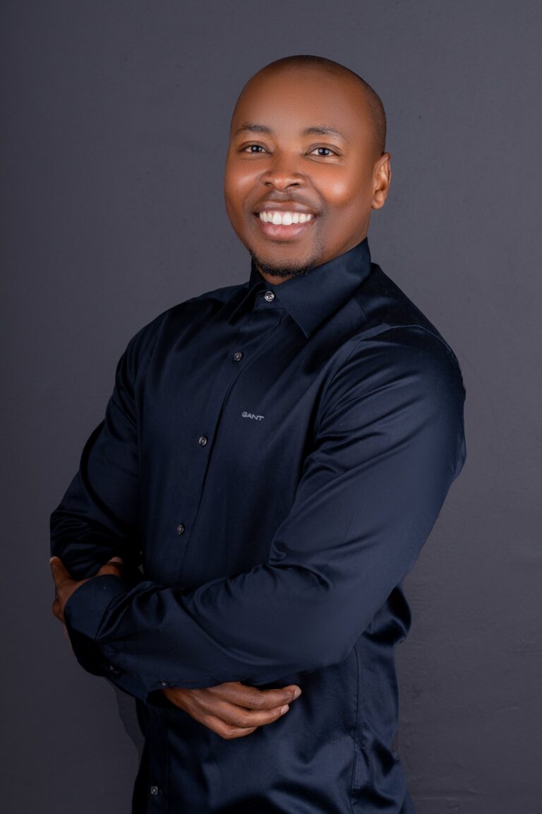 Professional headshot, navy shirt, arms crossed, bright smile, by Studio24.7