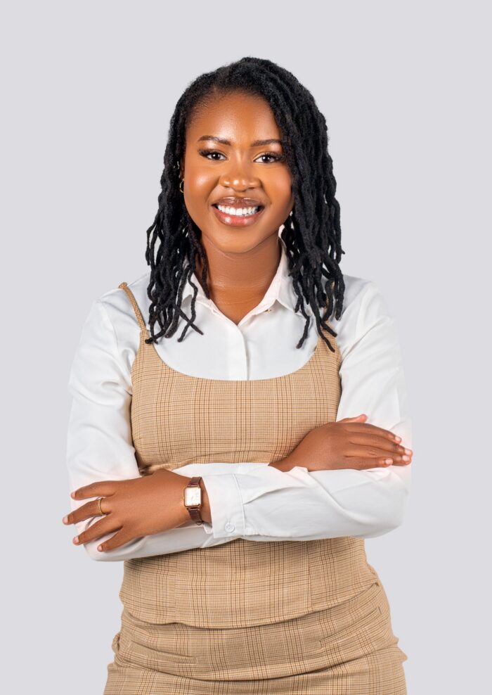 Professional headshot, white shirt and check pinafore, arms crossed, by Studio24.7